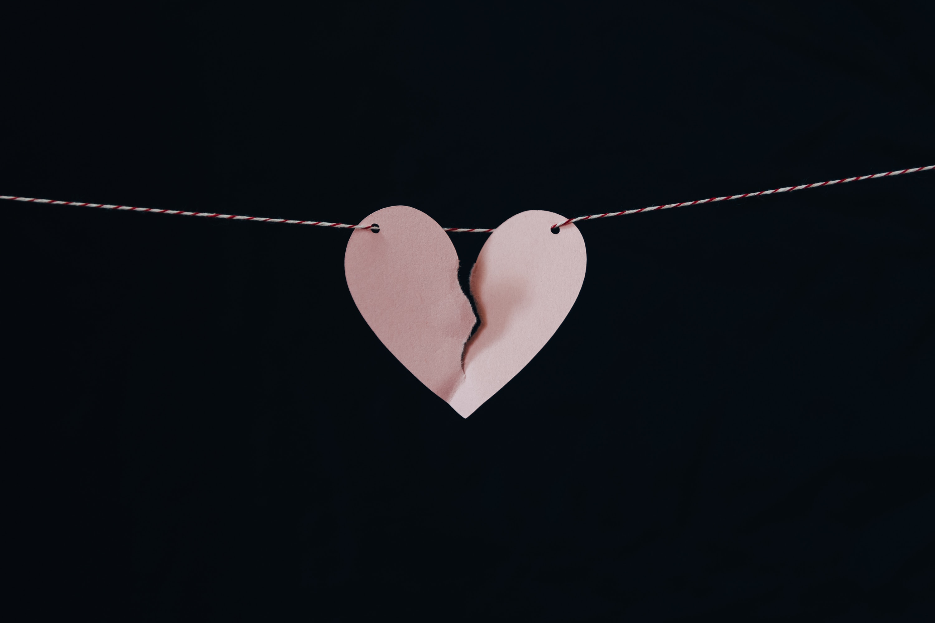 a broken paper heart hanging from a string representing a separation or divorce