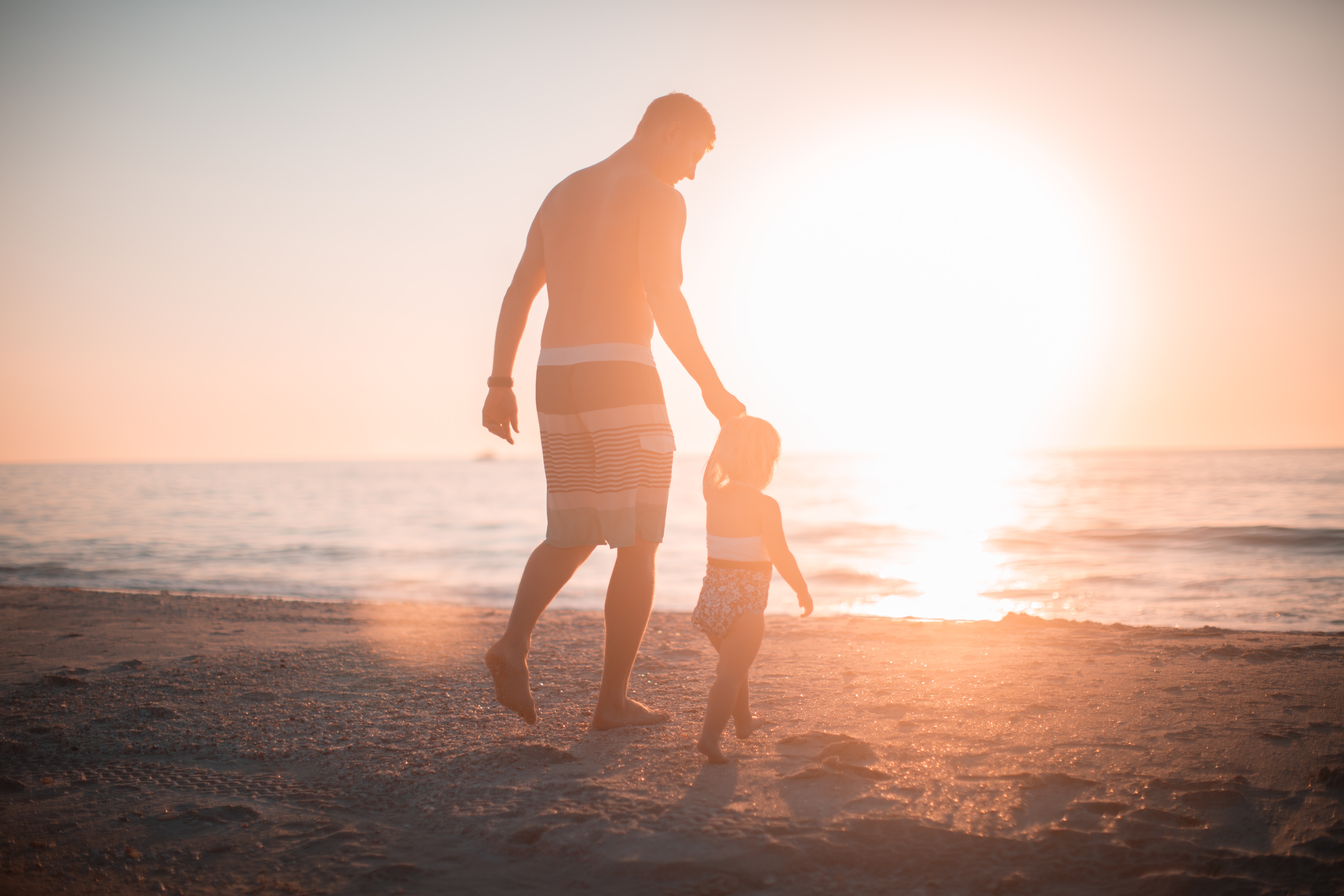 A man holding a child's hand on a beach representing being a step-father