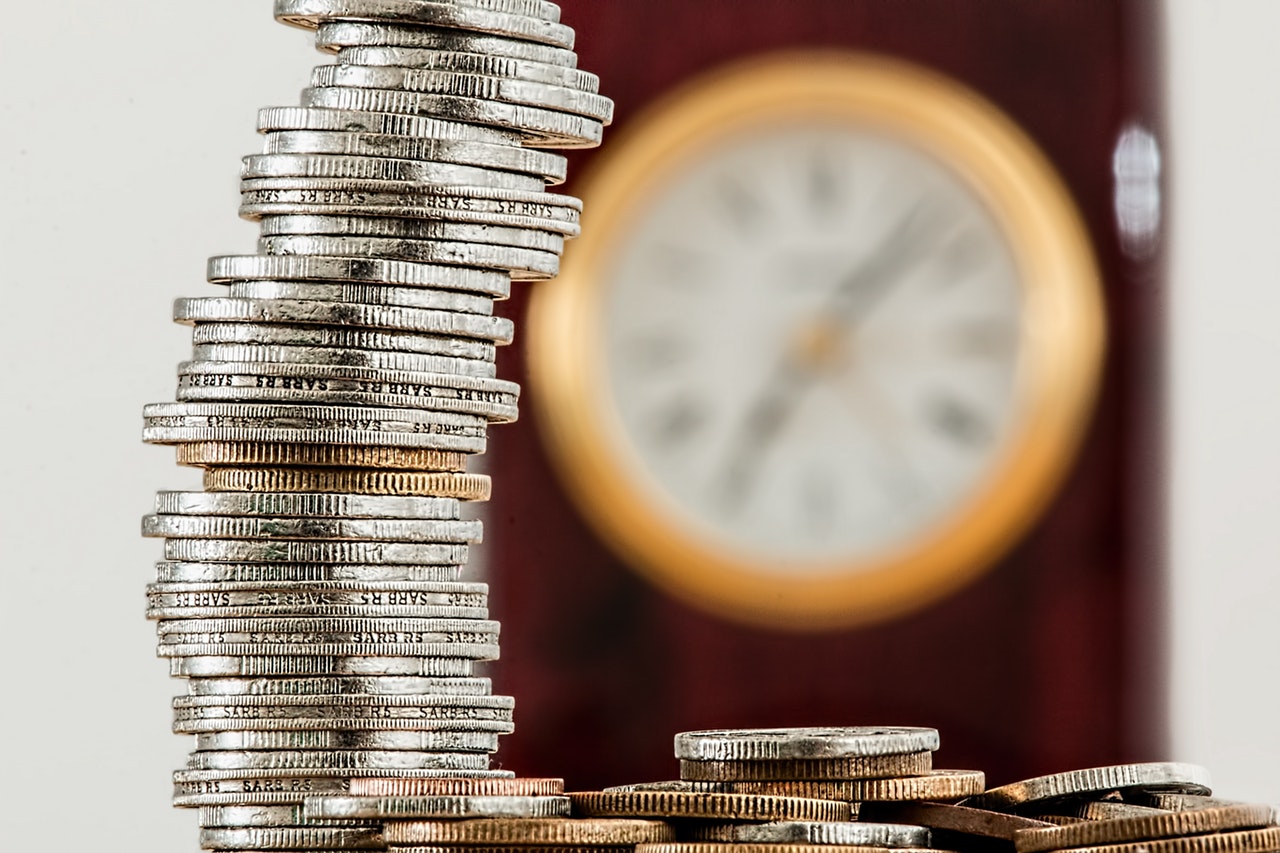A stack of coins next to a clock, representing interest that may be payable to beneficiaries if an estate is not distributed in a timely manner