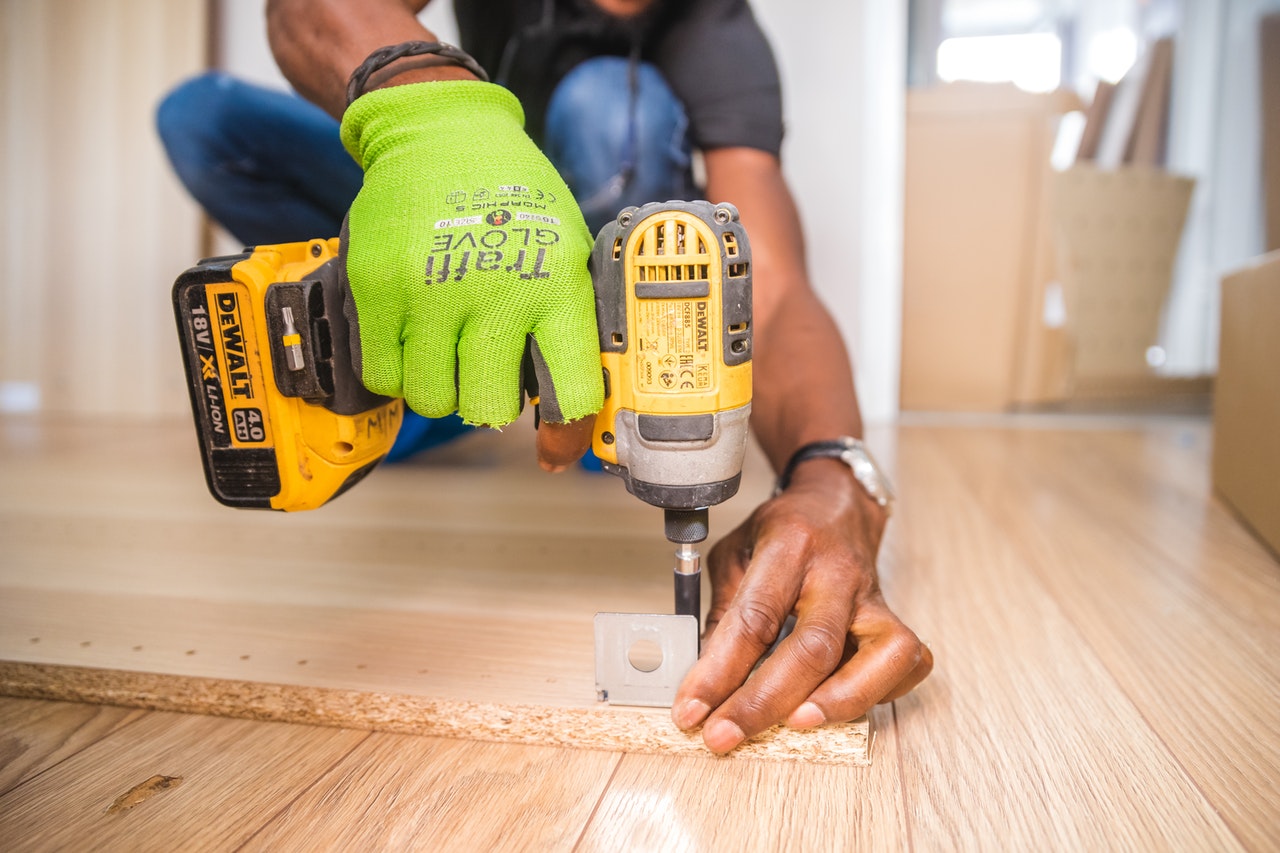 A person drilling a piece of wood representing extensive home renovations